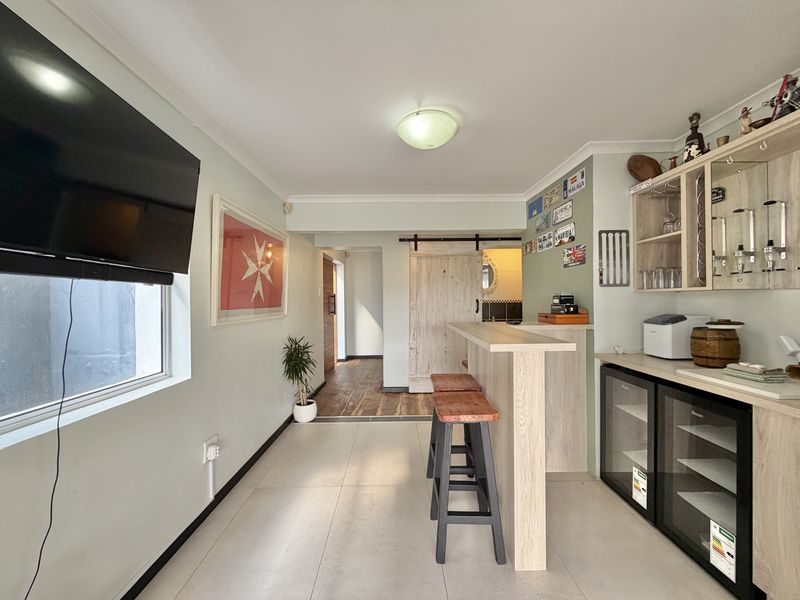 A well-appointed home bar area featuring a built-in counter, under-counter beverage refrigeration, custom cabinetry, and a rustic sliding barn door.