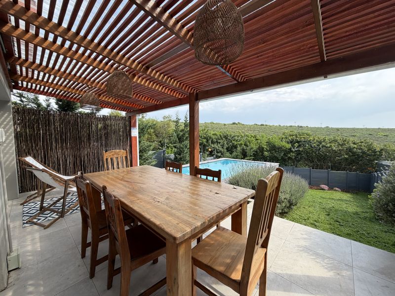Covered outdoor patio featuring a timber pergola, tiled flooring, and direct views over the swimming pool and garden area.