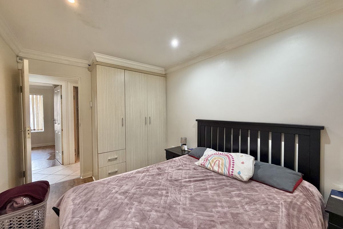 A bedroom featuring built-in wardrobes, crown molding, and recessed lighting, with a view into the adjacent hallway.