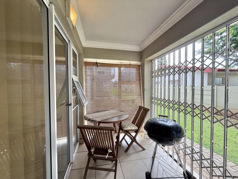 A covered patio area featuring tiled flooring, security gates, and sliding glass door access to the interior living space.