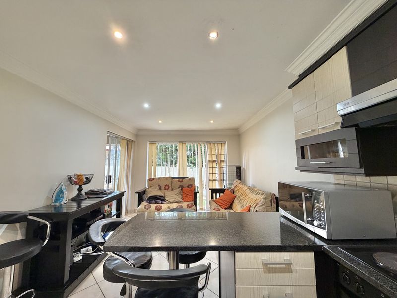 Open-plan living and kitchen area featuring granite countertops, modern cabinetry, recessed lighting, and tiled floors with access to an outdoor patio area.