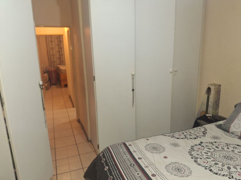 Bedroom featuring built-in cupboards and tiled flooring, with a view through the doorway into an adjacent room.