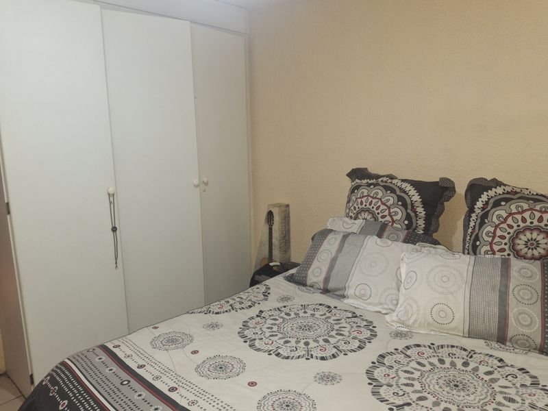 A bedroom featuring a built-in wardrobe with white doors and textured wall finishes.