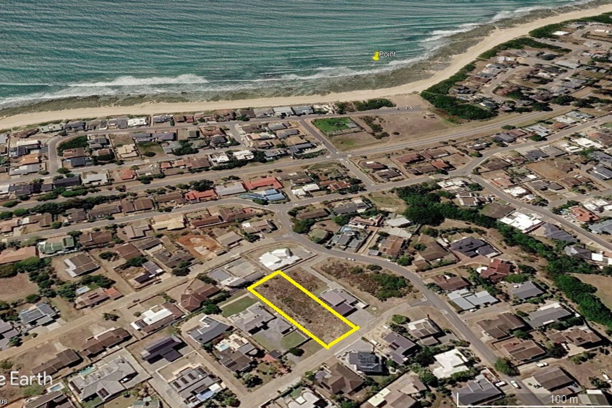 Aerial view of a vacant residential plot located in a coastal neighborhood, highlighting its proximity to the beach and surrounding residential development.