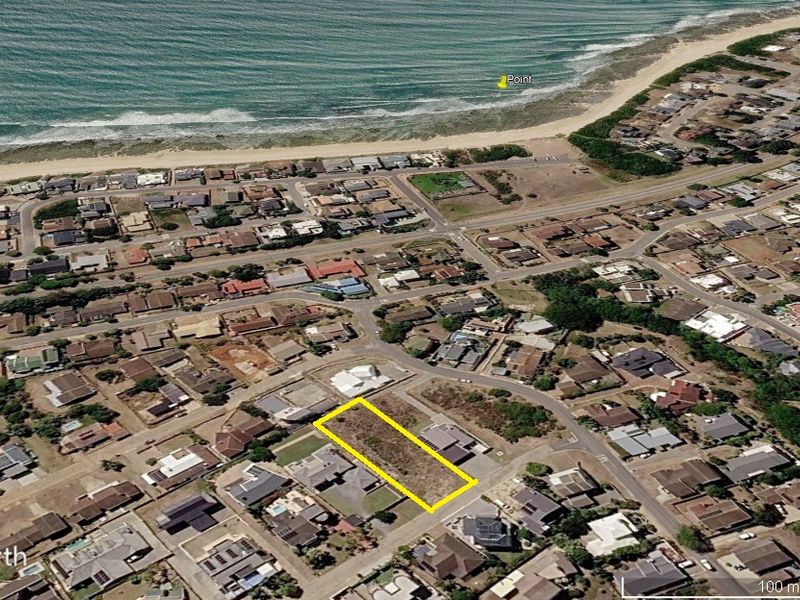 Aerial view of a vacant residential plot located in a coastal neighborhood, highlighting its proximity to the beach and surrounding residential development.