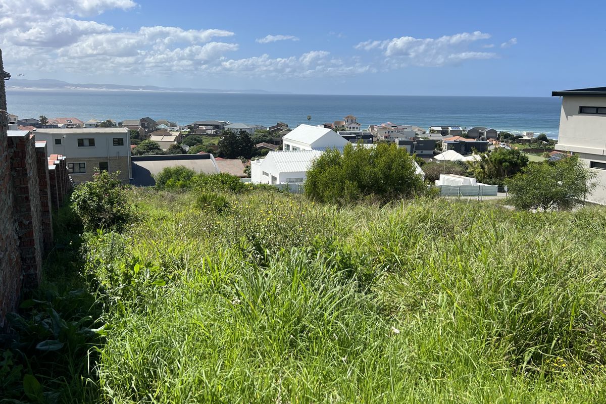 Elevated view of the coastal residential area and ocean from the vacant residential plot, featuring a brick boundary wall.