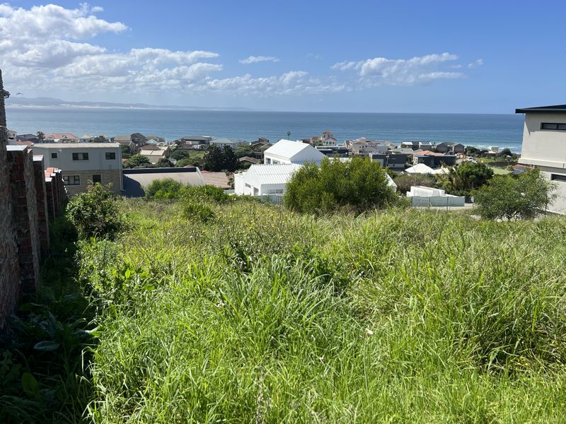 Elevated view of the coastal residential area and ocean from the vacant residential plot, featuring a brick boundary wall.