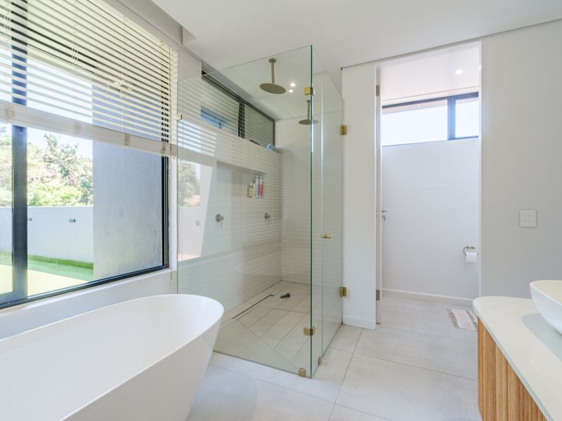 Modern bathroom featuring a sleek freestanding bathtub, a spacious glass-enclosed walk-in shower with dual heads, and a contemporary vanity with a vessel sink.