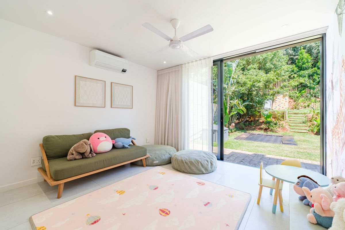 Bright living area featuring tiled floors, a ceiling fan, air conditioning, and large sliding glass doors opening onto a private garden.