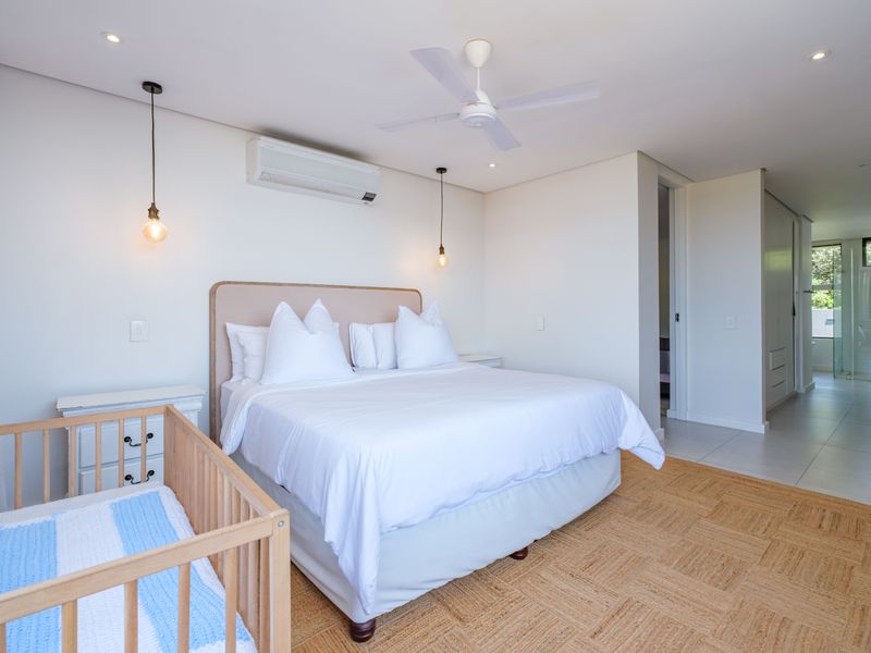 Spacious bedroom featuring tiled flooring, a ceiling fan, split-system air conditioning, and built-in cupboards, with an adjoining en-suite bathroom visible.