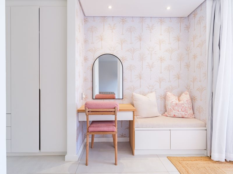 A well-appointed bedroom featuring a custom built-in vanity, integrated bench seating, and floor-to-ceiling wardrobe storage with modern finishes.