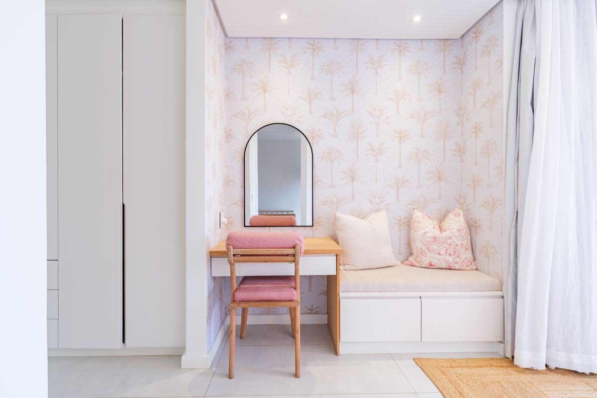 A well-appointed bedroom featuring a custom built-in vanity, integrated bench seating, and floor-to-ceiling wardrobe storage with modern finishes.