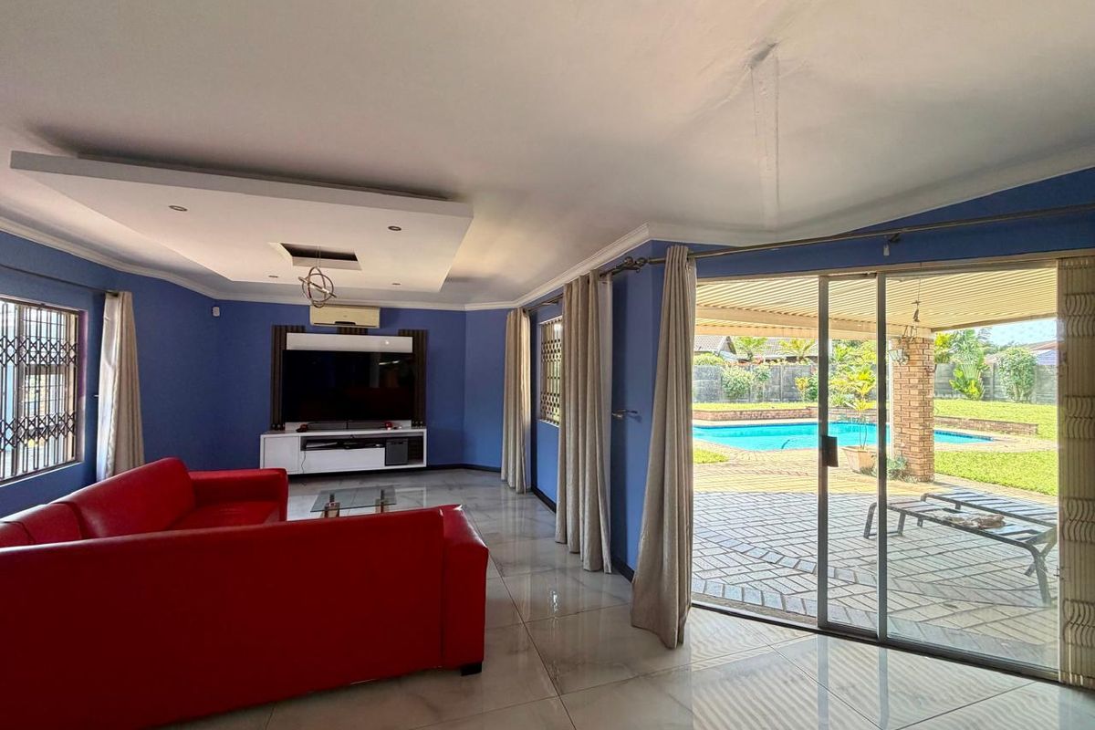 Spacious living room featuring tiled floors, a recessed ceiling, and large sliding glass doors providing direct access to the patio and pool area.