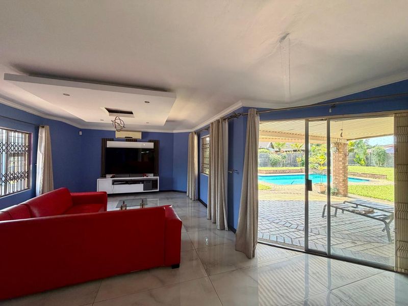 Spacious living room featuring tiled floors, a recessed ceiling, and large sliding glass doors providing direct access to the patio and pool area.