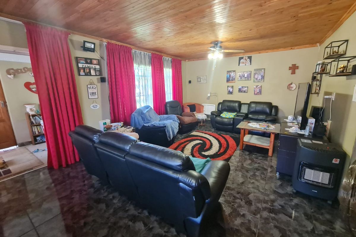 Spacious living room featuring a timber tongue and groove ceiling, ceiling fan, and dark tiled flooring.