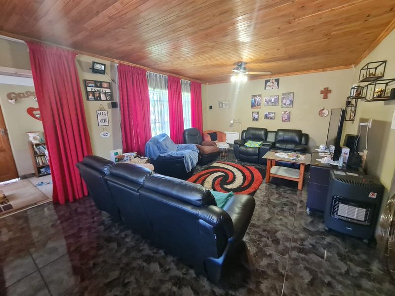 Spacious living room featuring a timber tongue and groove ceiling, ceiling fan, and dark tiled flooring.