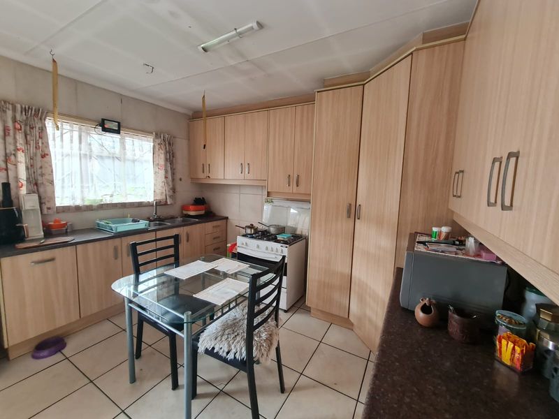 A functional kitchen featuring laminate cabinetry, tiled flooring, and a freestanding stove, offering a practical layout with potential for modern updates.