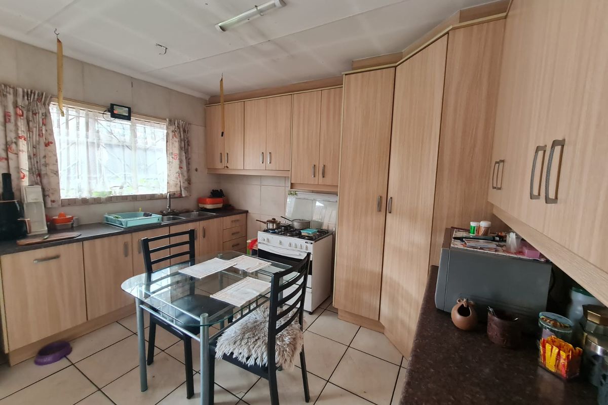 A functional kitchen featuring laminate cabinetry, tiled flooring, and a freestanding stove, offering a practical layout with potential for modern updates.