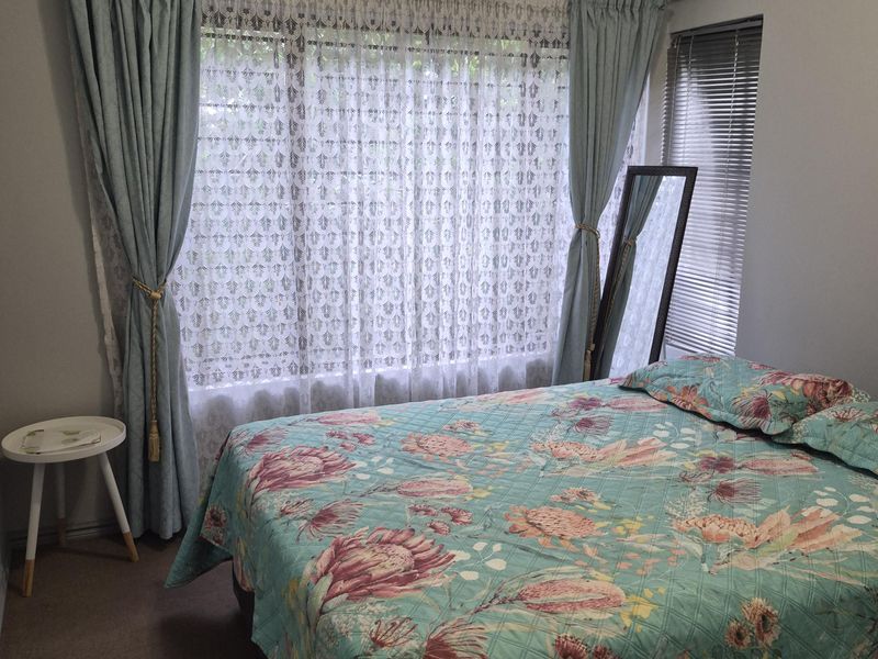 A bedroom featuring carpeted flooring, coving, and dual window treatments including curtain rails and venetian blinds.
