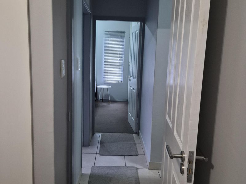 A functional hallway with tiled flooring connecting interior rooms, featuring neutral wall tones and standard internal door fixtures.