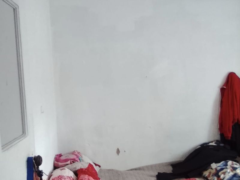A bedroom space featuring basic wall finishes and ceiling panels requiring maintenance and cosmetic updates.