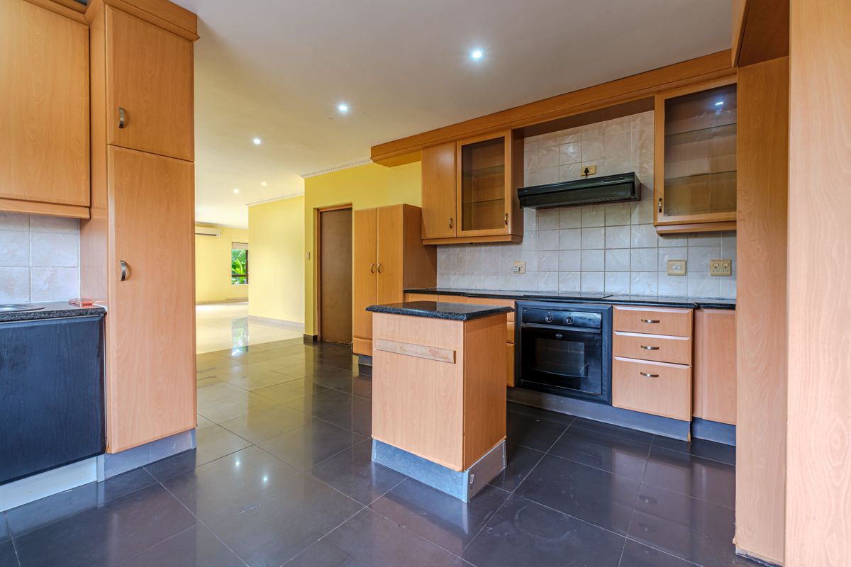 Spacious kitchen featuring light wood cabinetry, granite countertops, built-in oven, extractor fan, and dark tiled flooring, offering a functional layout for updates.
