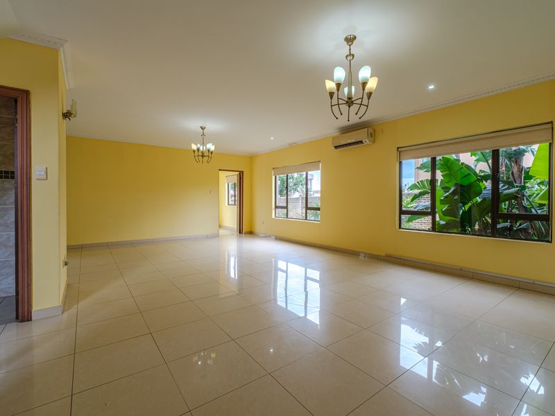 Spacious, sunlit living area featuring neutral tiled flooring, crown molding, and split-system air conditioning, offering a versatile blank canvas for interior design.