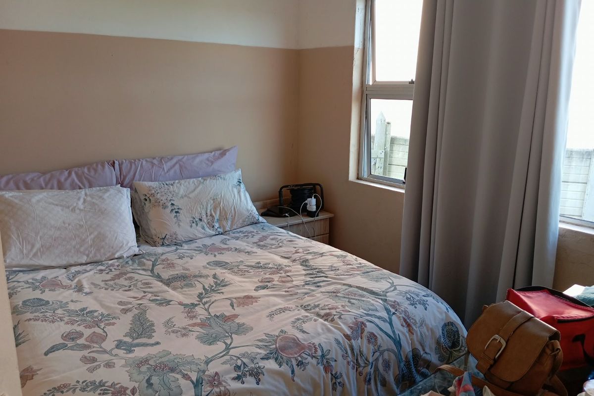 A bedroom featuring an aluminium window frame and two-tone wall finish, currently showing signs of wear and surface damage.