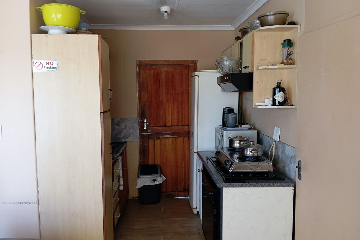 A compact kitchen featuring built-in cabinetry, tiled flooring, and a functional layout with a rear wooden door access.