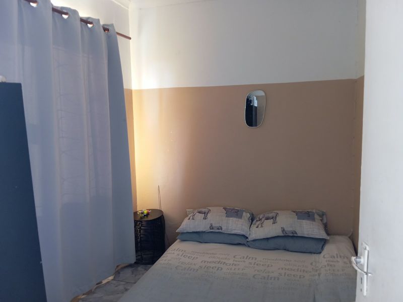 A compact bedroom featuring tiled flooring and a two-tone painted wall finish.