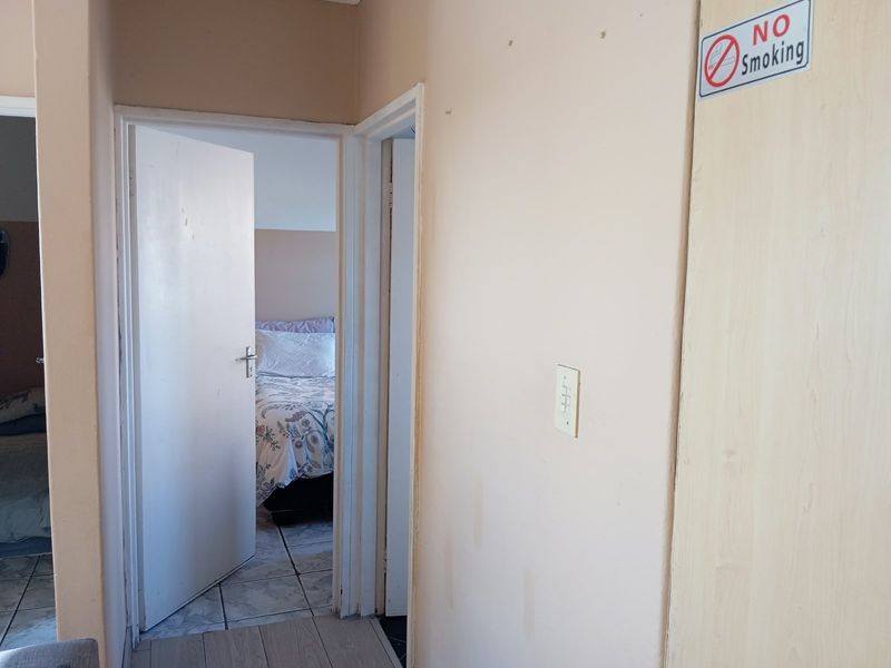 A view of a hallway connecting to a bedroom, featuring tiled flooring and neutral wall finishes.