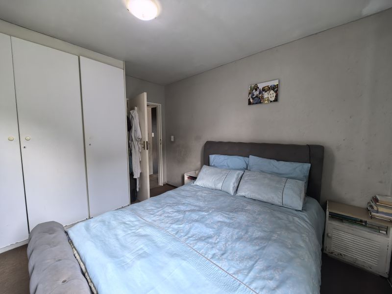 A bedroom featuring built-in cupboards and neutral wall finishes, requiring minor cosmetic updates to refresh the space.