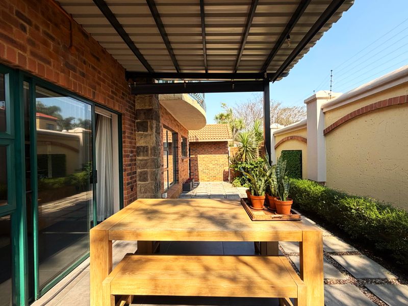A covered outdoor patio area featuring exposed brickwork, stone accents, and direct access to the home through large sliding glass doors.