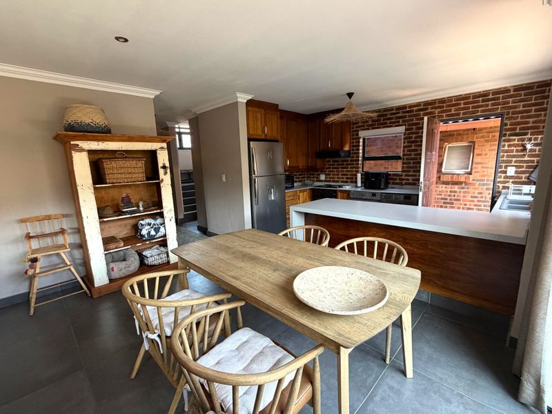 Open-plan kitchen and dining area featuring exposed brick walls, dark tiled flooring, and a functional kitchen island with integrated cabinetry.