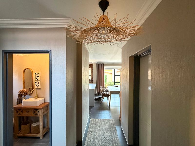 A well-maintained hallway featuring crown molding and tiled flooring, providing a clear transition between the bathroom and the open-plan living area.