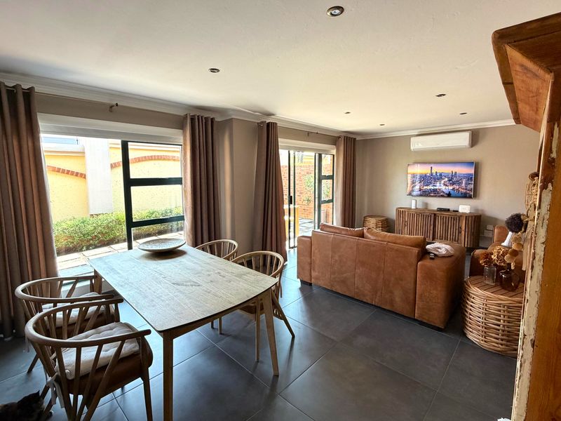 Spacious open-plan living and dining area featuring large format floor tiles, recessed lighting, split-system air conditioning, and direct access to the outdoor patio.