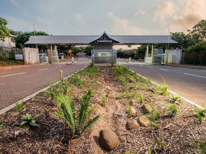 A well-maintained secure entrance gatehouse for the residential estate, featuring paved dual-lane access and landscaped central garden beds.