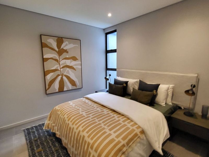 A modern, well-maintained bedroom featuring neutral wall tones, recessed downlighting, tiled flooring, and a built-in cupboard.