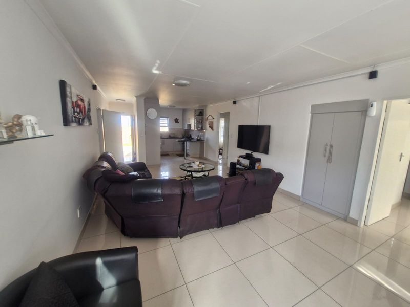 Open-plan living area featuring tiled flooring, a built-in cupboard, and a functional kitchen space with cabinetry and integrated fixtures.