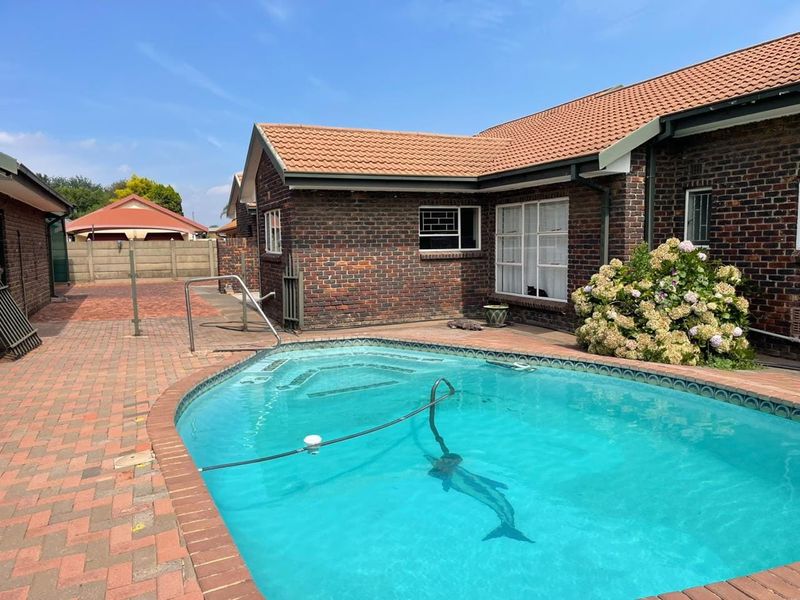 A private swimming pool area featuring brick paving, face brick exterior walls, and a tiled roof, providing a functional outdoor space.