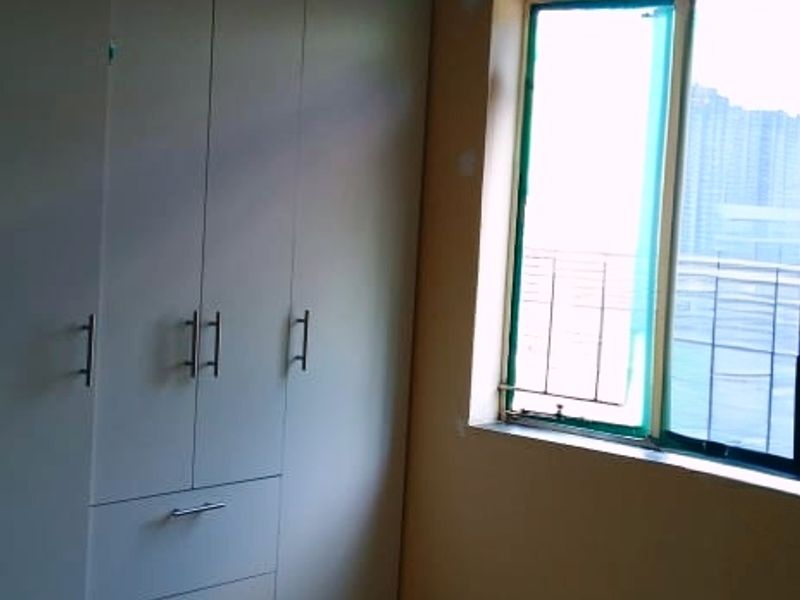 A compact bedroom featuring tiled flooring, a built-in wardrobe, and a window providing natural light.
