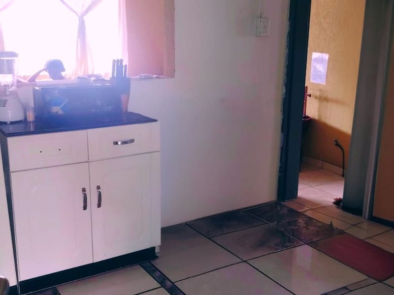 A kitchen area featuring built-in cabinetry and tiled flooring, with a pass-through window connecting to an adjacent space.