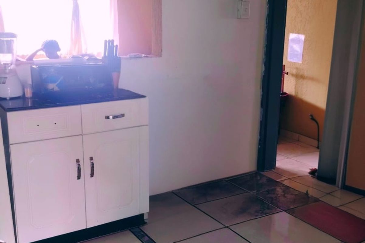 A kitchen area featuring built-in cabinetry and tiled flooring, with a pass-through window connecting to an adjacent space.