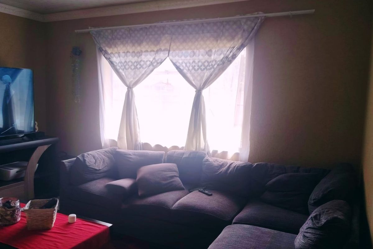 A cozy living room featuring a large window with natural light and decorative cornice detailing.