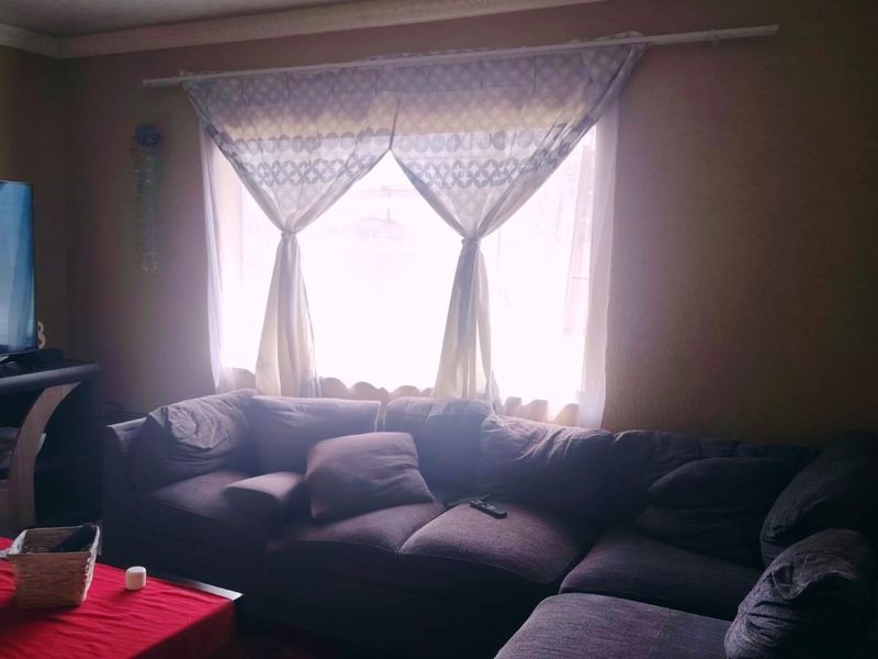A cozy living room featuring a large window with natural light and decorative cornice detailing.