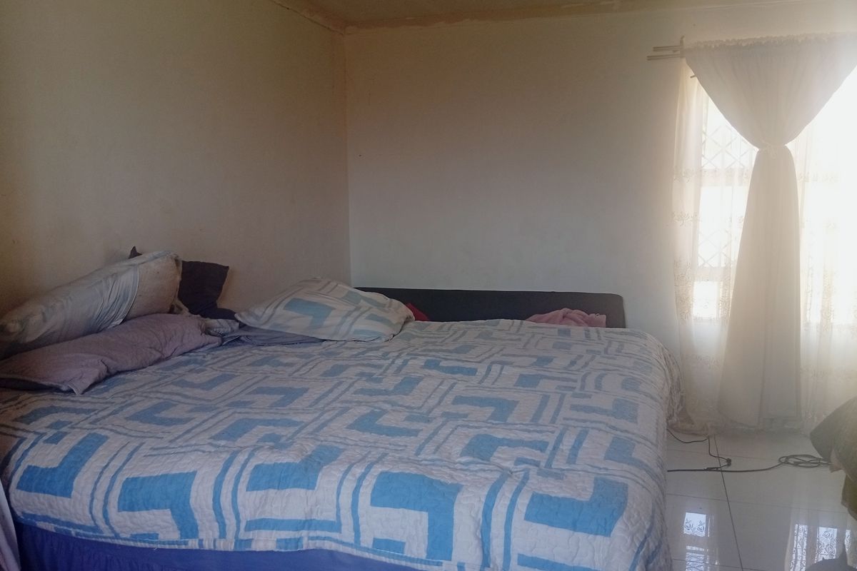 A bedroom featuring tiled flooring and natural light from a window with a curtain rod.