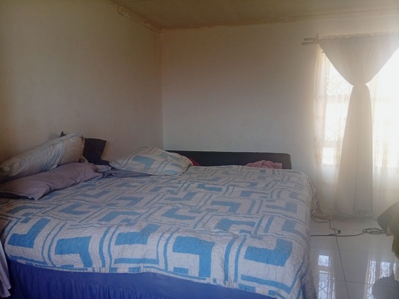 A bedroom featuring tiled flooring and natural light from a window with a curtain rod.