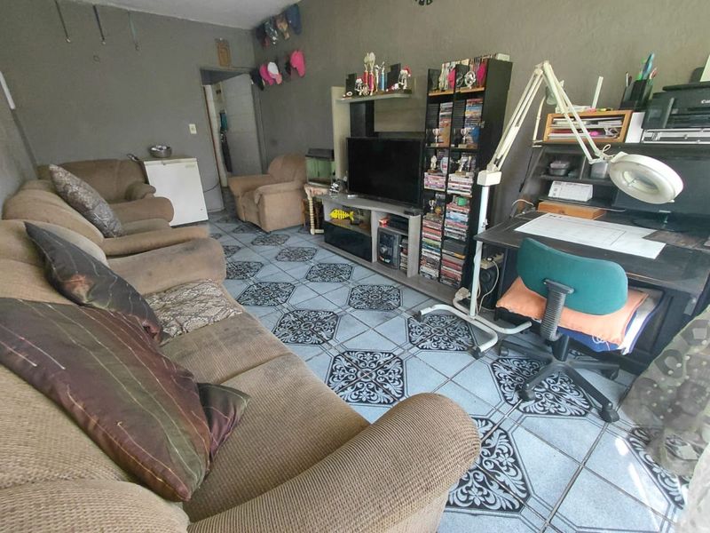 A living room area featuring patterned ceramic floor tiles and neutral wall finishes, offering a functional space for relaxation and home office use.
