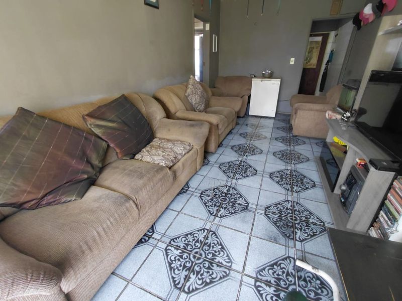 A living room area featuring patterned ceramic floor tiles and neutral wall finishes, offering a functional space ready for cosmetic updates.