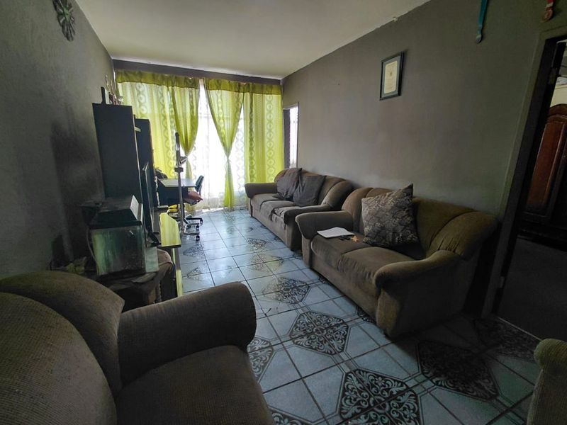 A living room featuring patterned ceramic floor tiles and natural light from a window with curtains.